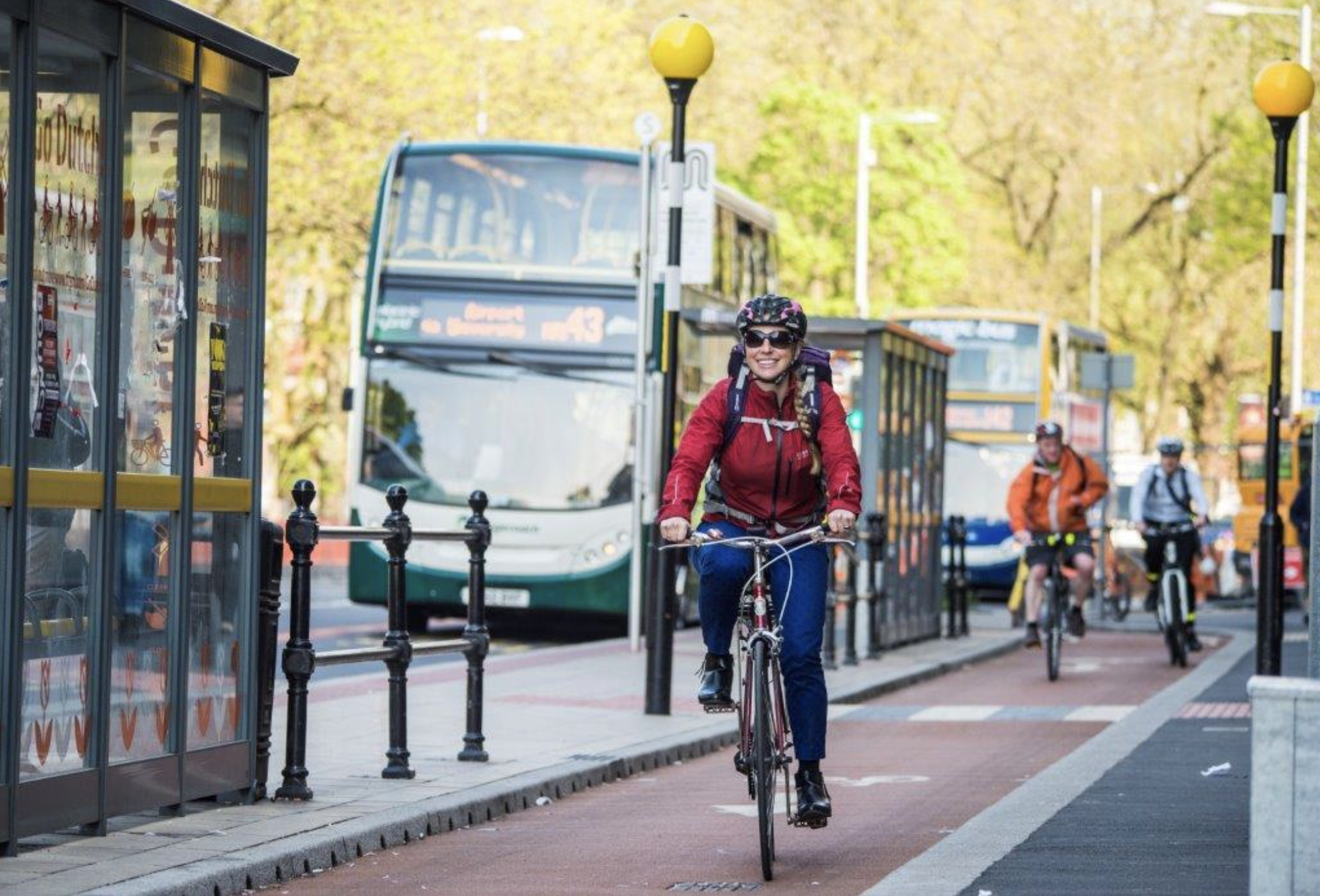 Image of a smiling female cycling riding down a cycle lane on Oxford Road, Manchester.