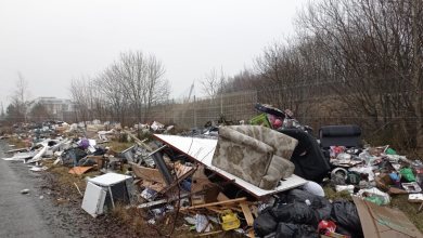 Image of a large pile of waste dumped by the side of the road. Items include a large sofa chair on top of other industrial waste.