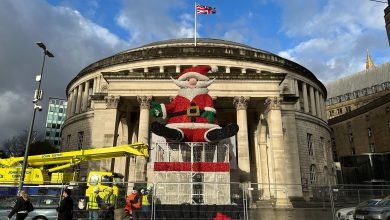A giant sparkly Santa Claus figure sitting on top of giant wire box, in front of Manchester's Central Library