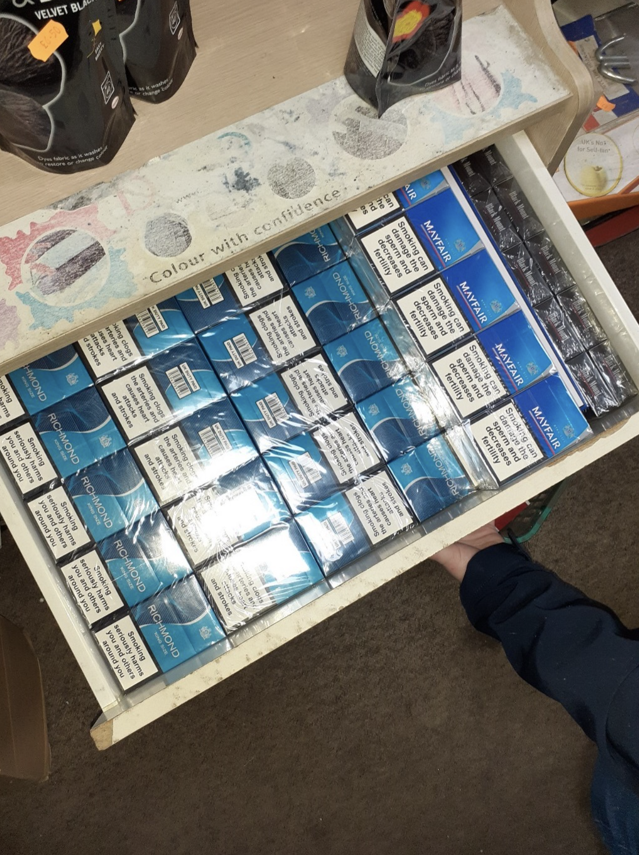 Image of packs of cigarettes stacked inside an open drawer.