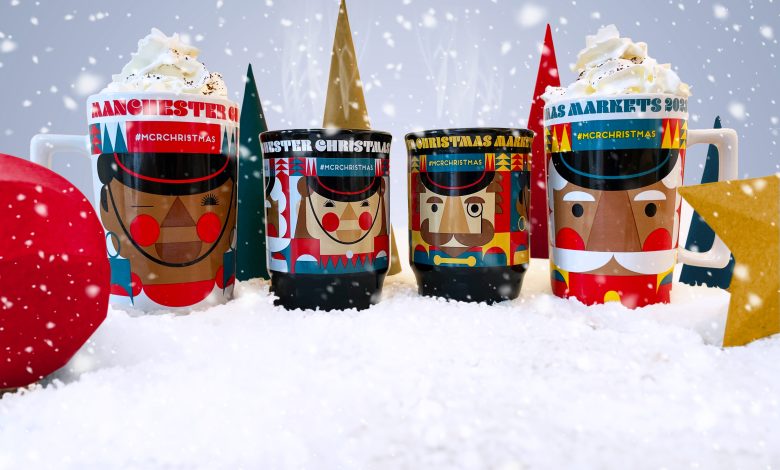 4 drinking mugs lined up in a row standing in artificial snow.  Each mug is brightly coloured with Christmas Nutcracker designs on them.