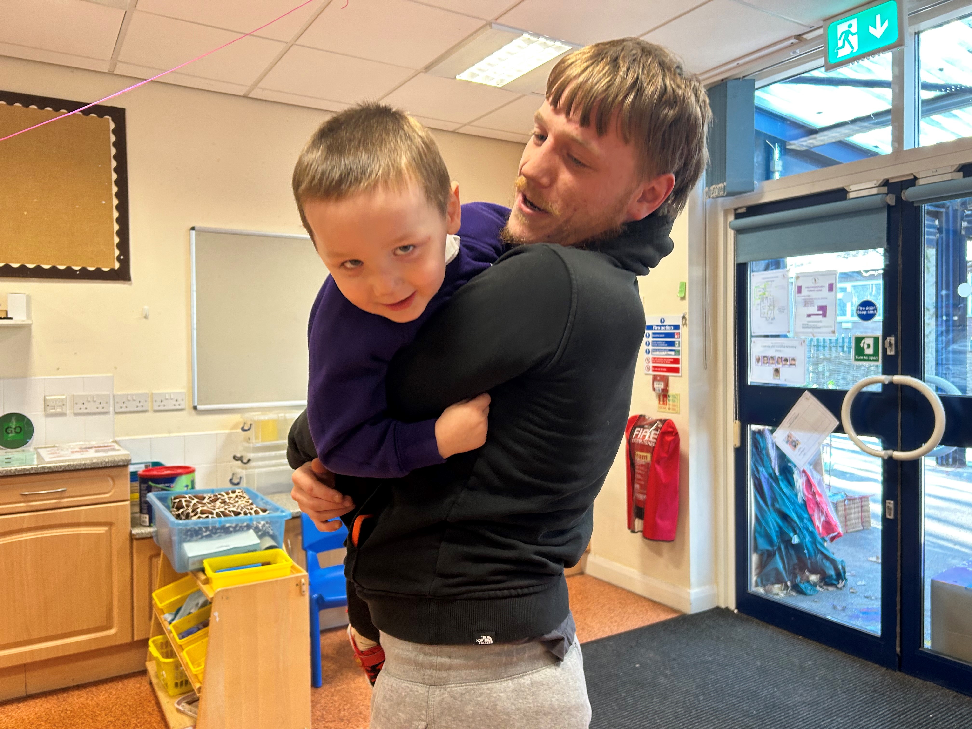 Dad Joshua holding his son as they play 