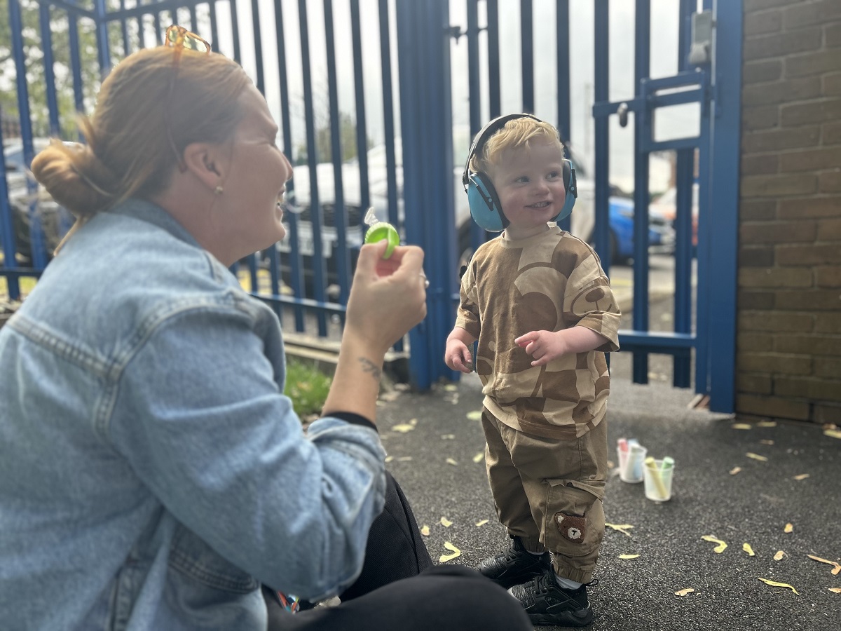 Reegan Samuels smiling as he plays with bubbles with Lauren Eaton