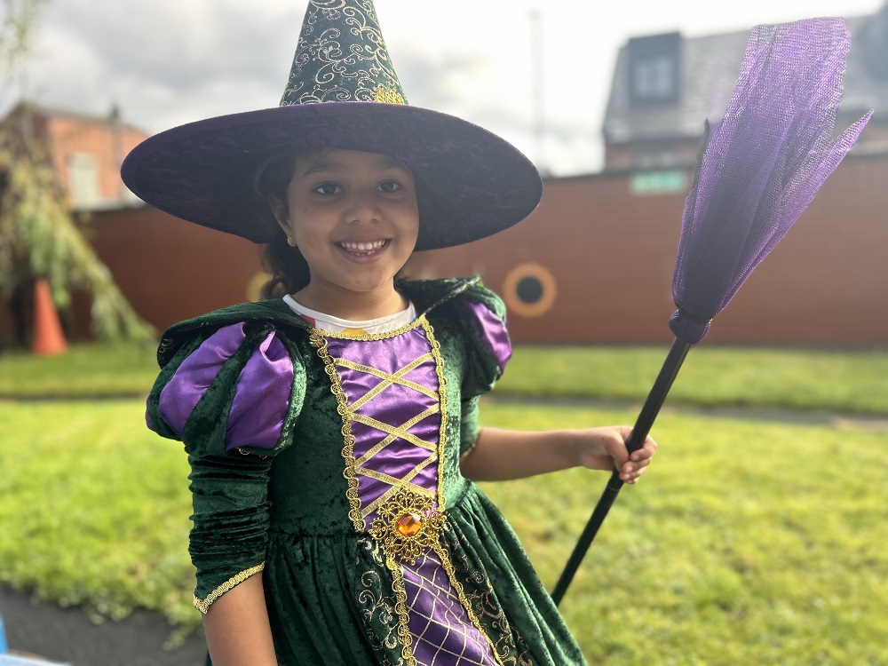 Zahra Khan dressed up as a witch in a purple and green dress and hat