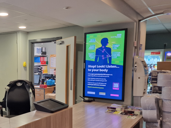 Screen in reception area showing graphic from Upper GI cancer awareness campaign