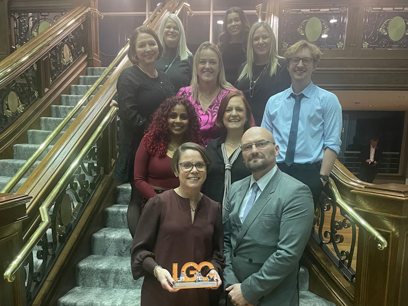 Salford City Council officers stood on the stairs with the LGC award