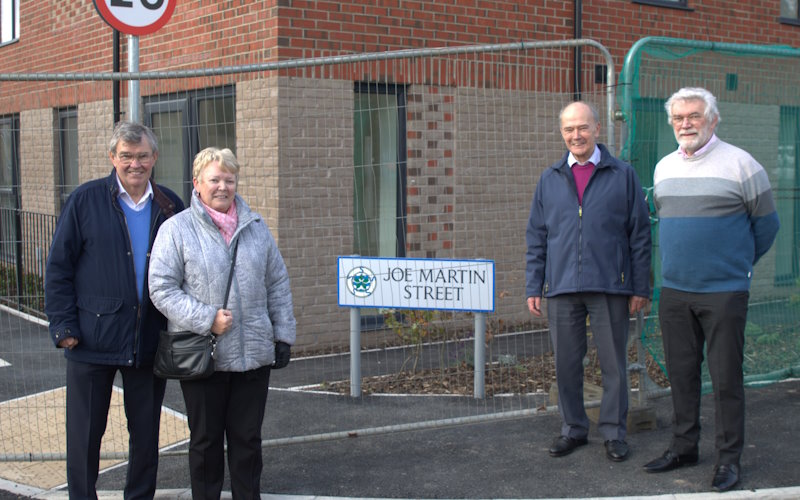 Four friends and family of Joe Martin in front of the street name sign