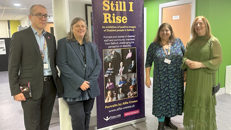 Tom and others stood in front of the Still I Rise pull up banner