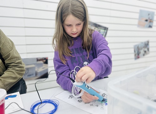 A young girl tries out a 3D pen