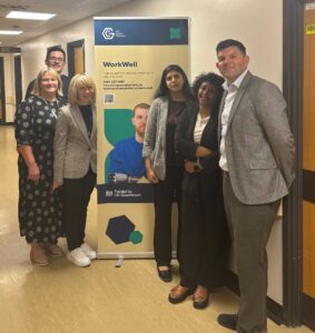 Six people stood in hospital corridor with WorkWell sign