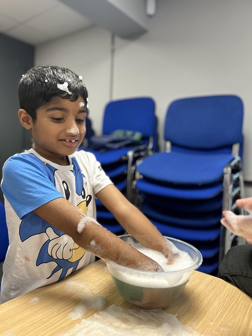 A child smiling as they play at POINT 